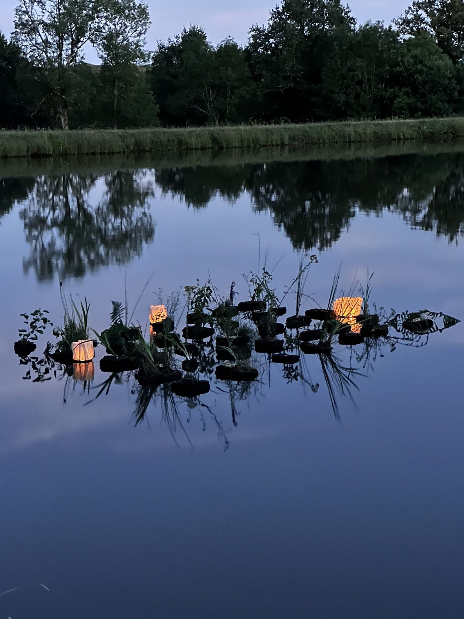 The floating cork and bamboo island with its lanterns lit on the lake